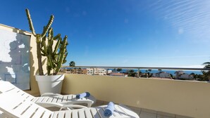 A balcony with white plastic chairs, a potted cactus, and a view of the sea and buildings. - Como siempre by Interhome (Vinarós)