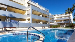 A swimming pool with a tiled deck, surrounded by a multi-story building with balconies. - Como siempre by Interhome (Vinarós)