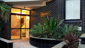 A hotel entrance with a sign reading "ENCORE," a glass door, and a brick wall. - Majestic, Private Luxury Apartment - Harbourside (Darlinghurst)
