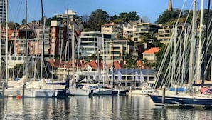 A marina with boats docked, surrounded by residential buildings and a church spire in the background. - Majestic, Private Luxury Apartment - Harbourside (Darlinghurst)
