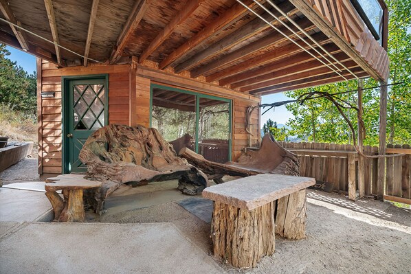 Eine rustikale Holzhütte mit einer grünen Tür, einem großen Holztisch und einer Bank.