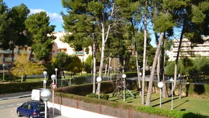 Un quartier résidentiel avec une rue, des voitures garées et un terrain de jeux.