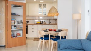 Une cuisine moderne avec des meubles blancs, une table à manger entourée de chaises bleues et un luminaire suspendu.