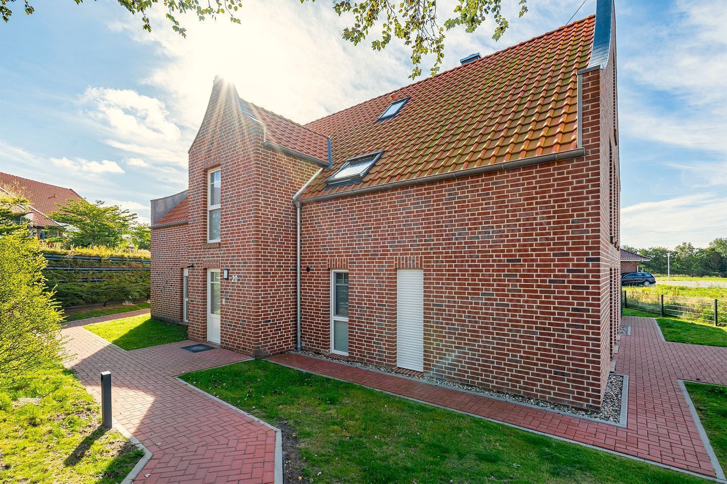 A two-story brick building with a red-tiled roof, a small window, and a paved driveway.