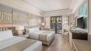 Habitación de hotel con dos camas, un escritorio, una silla, un televisor y un balcón con vistas a palmeras.
