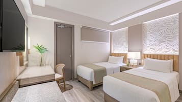 Habitación de hotel con dos camas, televisor, escritorio y una silla.