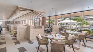 Un moderno vestíbulo de hotel con techo alto, zona de estar abierta y grandes ventanales que ofrecen vistas a la piscina y al área exterior.