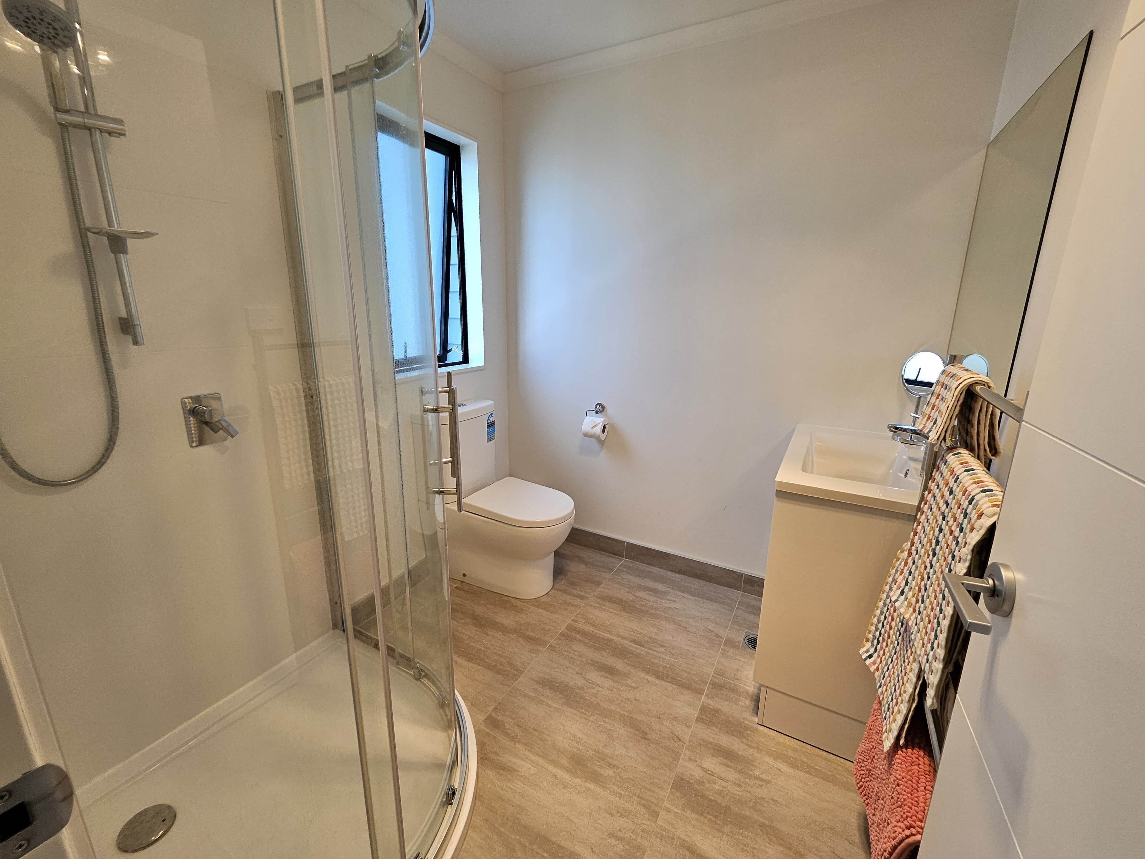 Un bagno moderno con cabina doccia in vetro, un water e un lavandino.