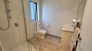 Un bagno moderno con cabina doccia in vetro, un water e un lavandino.