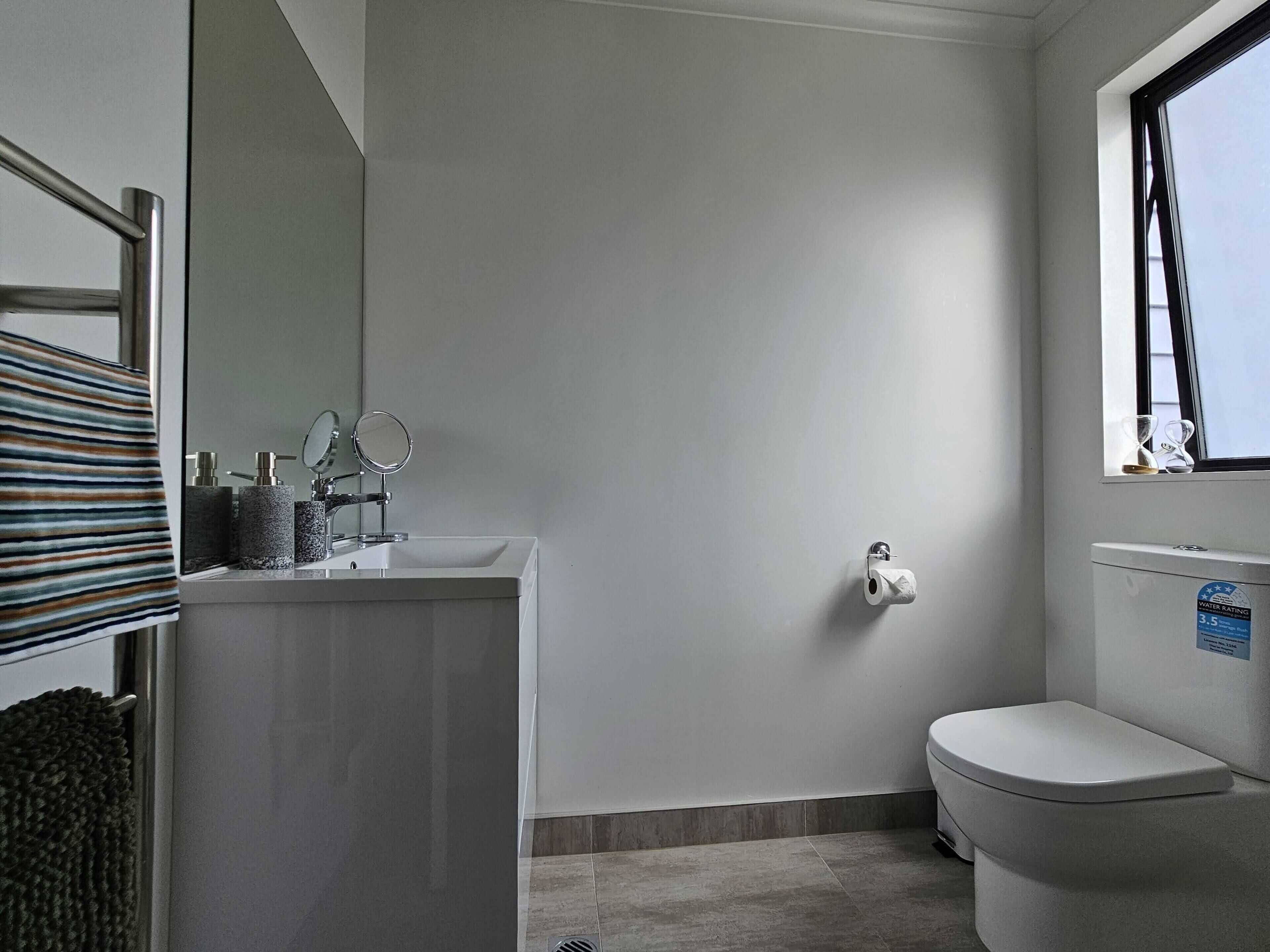 A modern bathroom with a white sink, mirror, and toilet.
