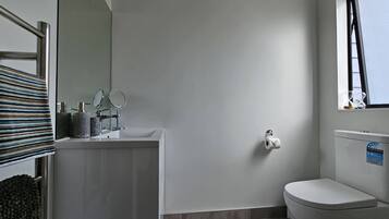 A modern bathroom with a white sink, mirror, and toilet.