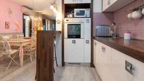 Une cuisine moderne avec des meubles blancs, un four à micro-ondes et un grille-pain. On y trouve également un coin repas avec une table et des chaises en bois.