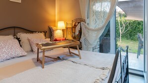 Une chambre à coucher avec un lit, une table de chevet, une lampe et une vue sur l’extérieur.