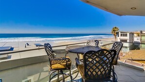 Ein Balkon mit Tisch und Stühlen mit Blick auf einen Strand.