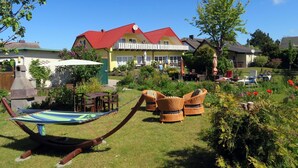 Ein Haus mit rotem Dach, einem Balkon und einem Garten mit Gartenmöbeln.