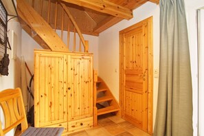 A wooden staircase leading to a loft area with a wooden wardrobe and a door.