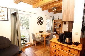 A cozy kitchen with a wooden table, chairs, a coffee maker, and a clock on the wall.