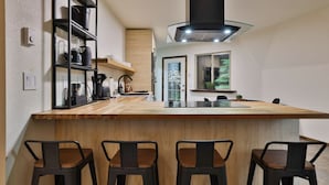 Une cuisine moderne dotée d’un îlot central, de tabourets de bar et d’une hotte noire.