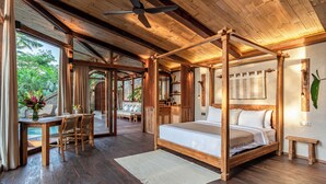 A spacious bedroom with a four-poster bed, a wooden ceiling, and a view of the outdoors. - Casa Pohon Ubud (Ubud)