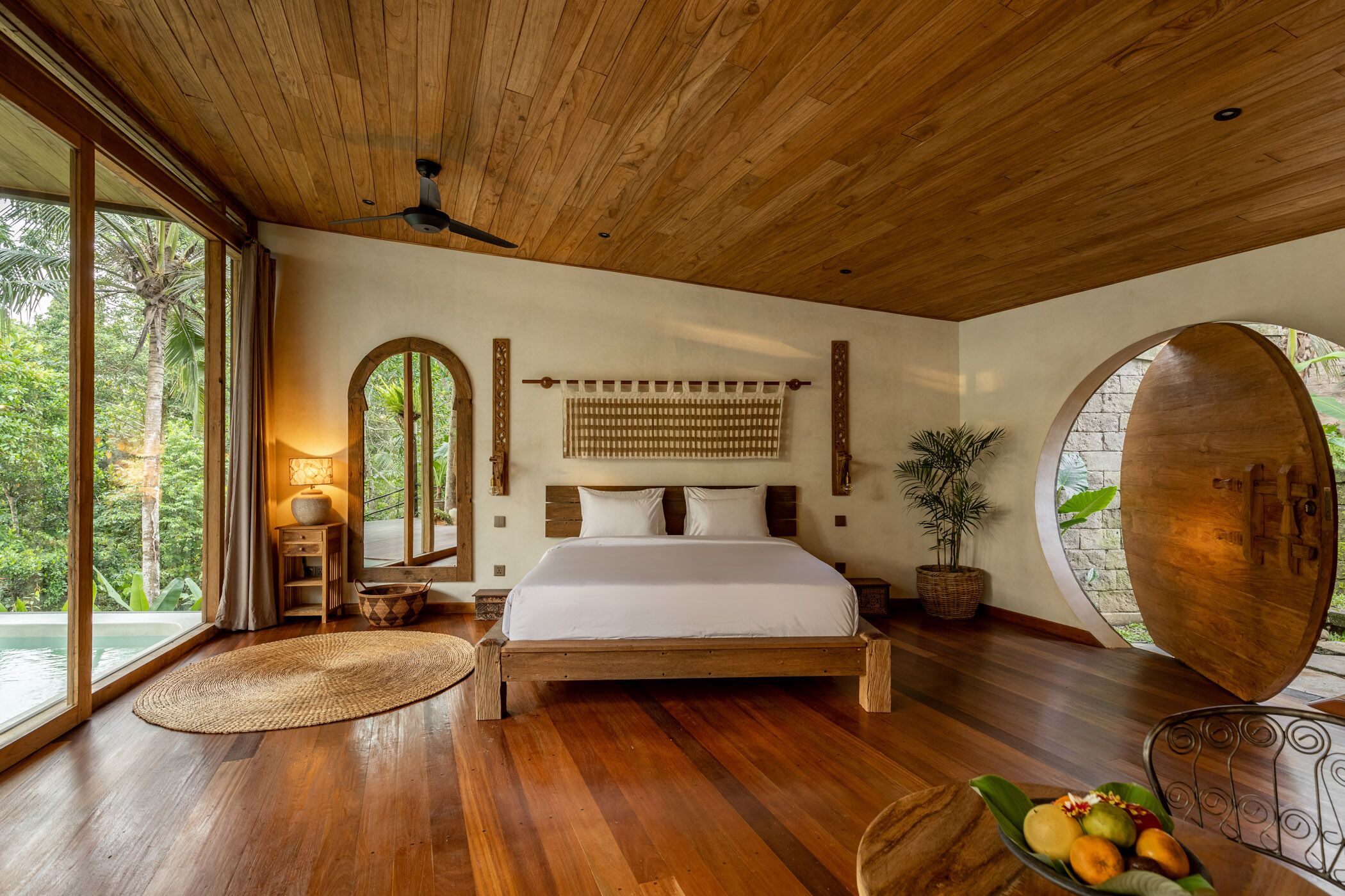 Quarto espaçoso com cama grande, piso de madeira, ventilador de teto e vista para o exterior.