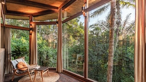 A room with a large glass window, a wooden ceiling, and a woven mat on the floor. - Casa Pohon Ubud (Ubud)