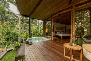 A wooden deck with a pool, surrounded by lush greenery. - Casa Pohon Ubud (Ubud)