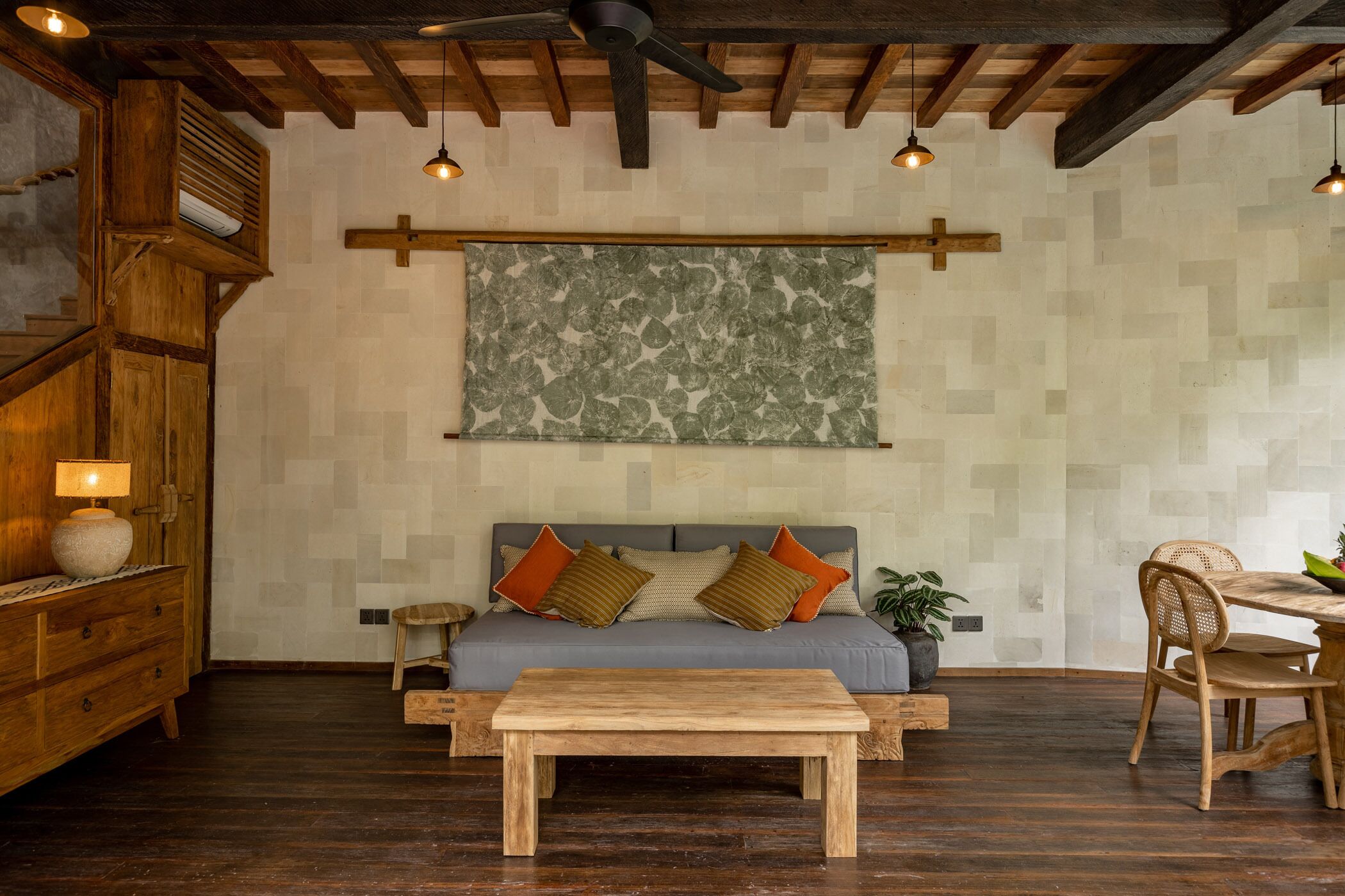 Un salon chaleureux avec un canapé en bois, une table basse en bois et un coin repas comprenant une table et des chaises en bois.