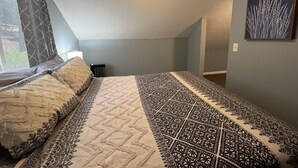Ein Schlafzimmer mit Bett, Heizkörper, einem fenster mit Vorhängen und einem Gemälde an der Wand.