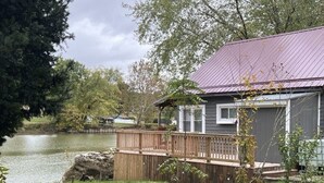 Ein Haus mit einer Metalldach, einer Holterrasse und Blick auf einen See.