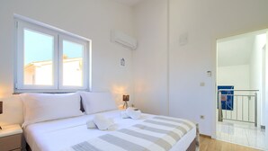 A bedroom with a bed, bedside tables, a window, and an air conditioning unit. - Bernarda by Interhome (Krk/Kornić)