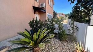 A residential building with a small garden area featuring a palm tree, a potted plant, and a gravel pathway. - Bernarda by Interhome (Krk/Kornić)