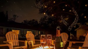 A table set with chairs, a bottle of wine, and glasses, with a fire feature in the center. - * When in Naples *Heated Pool Villa, 2mil downtown (Naples)