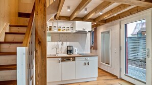 Una cocina moderna con vigas de madera, lavavajillas integrado y ventana con vistas a una casa.