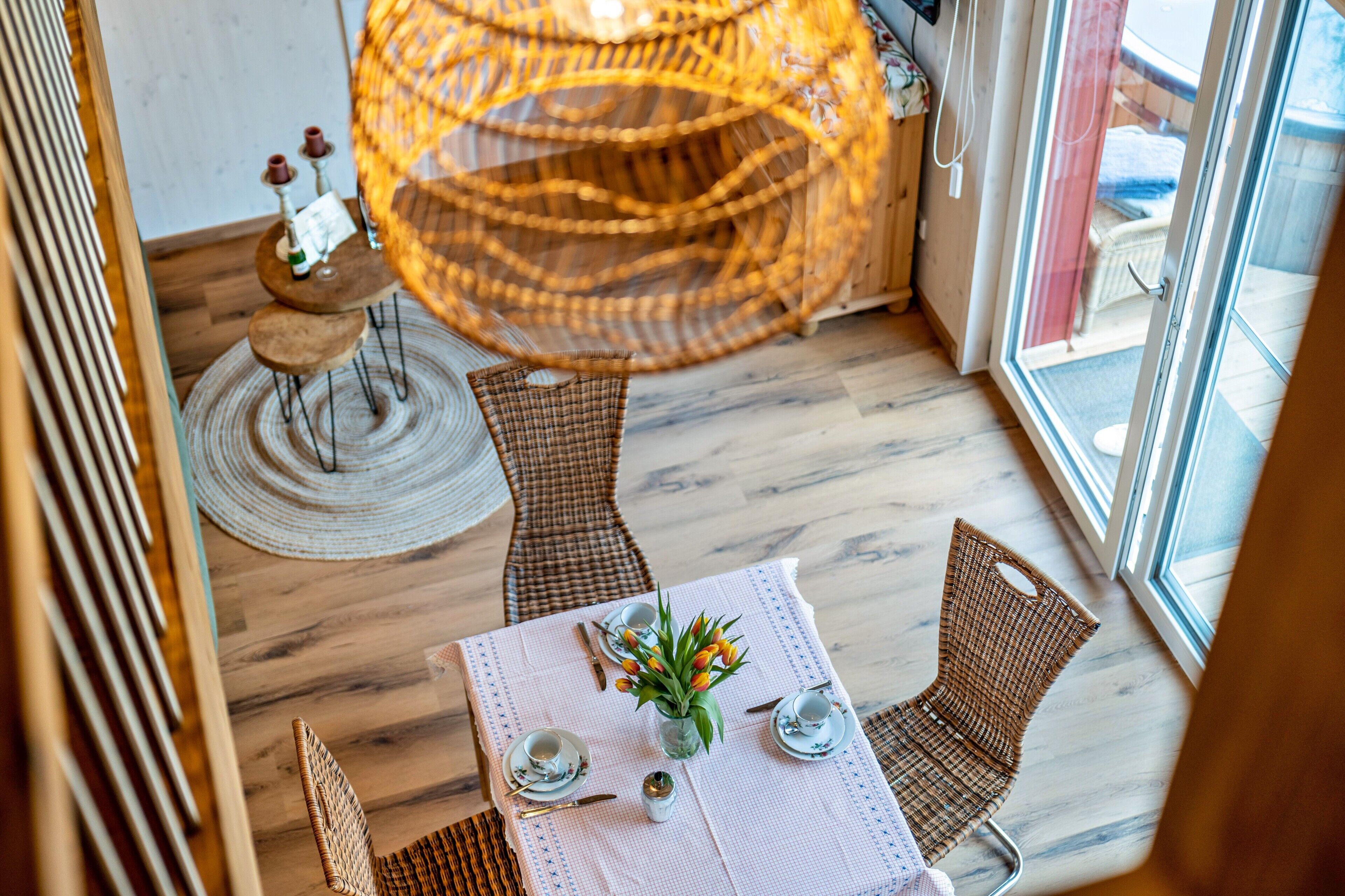 En matplats med flätade stolar, ett runt bord och en hängande lampa.