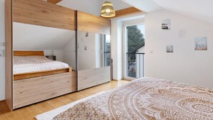 Un dormitorio con cama, armario, una mesita y ventana.