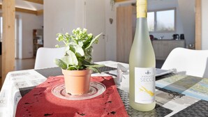 Una mesa con una botella de vino, una planta en maceta y un paño rojo.