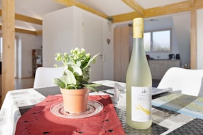 Ein Tisch mit einer Weinflasche, einer Topfpflanze und einer roten Tischdecke.