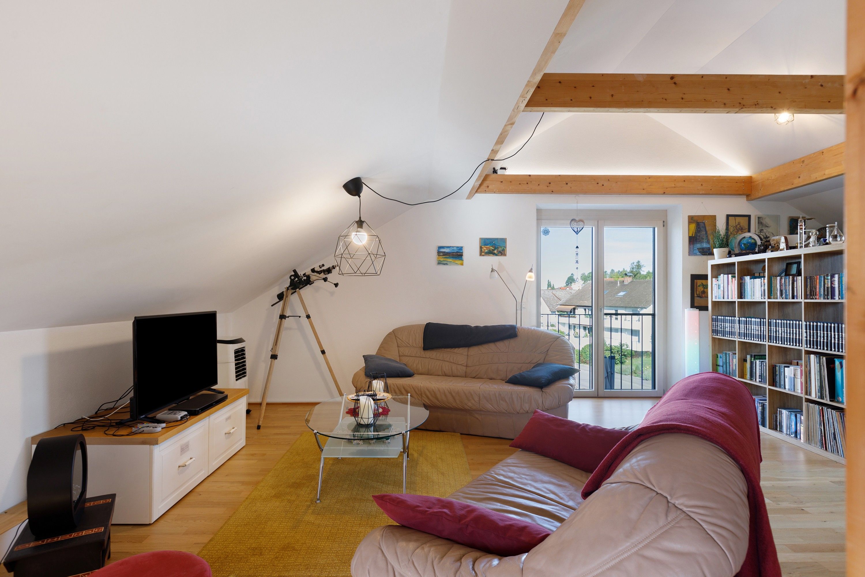 Ein gemütliches Wohnzimmer mit einer Couch, einem Couchtisch, einem Fernseher und einem Bücherregal.