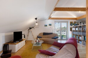 A cozy living room with a sofa, a coffee table, a TV, and a bookshelf.