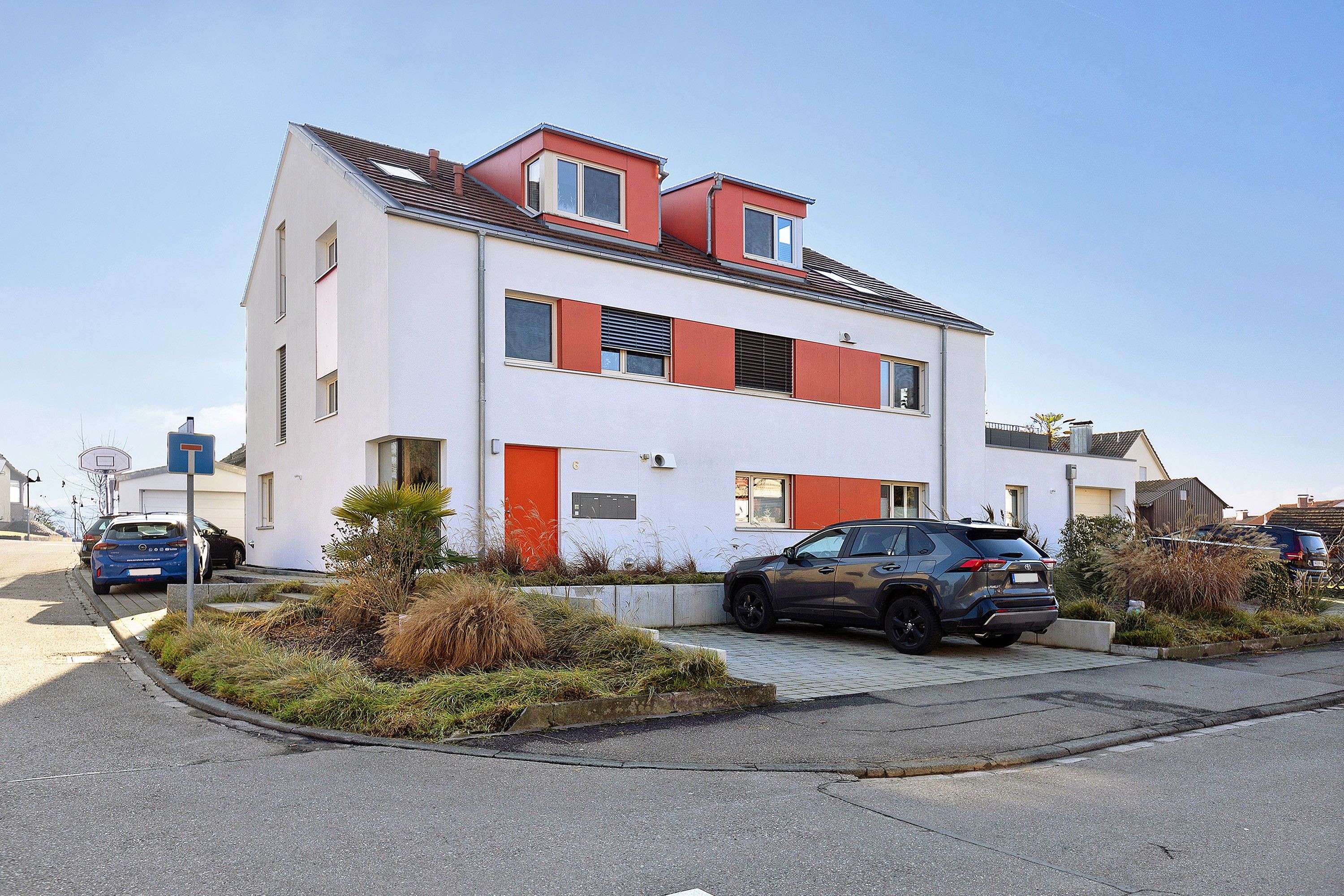 Ein zweigeschossiges Wohngebäude mit flachem Dach, einer Garage und einer Auffahrt.