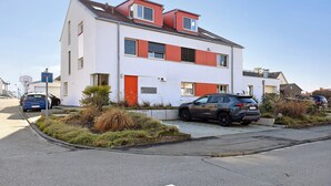 Un edificio residencial de dos pisos con techo plano, garaje y entrada para vehículos.