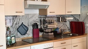 Une cuisine avec des armoires blanches, une cuisinière, un évier et un ventilateur de plafond.