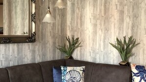 Un salon avec un canapé en cuir marron, une table basse en bois et un miroir au mur.