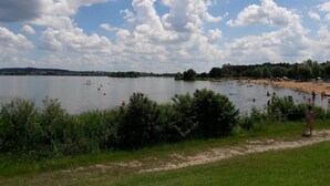 Een meer met een zandstrand en een grasveld op de voorgrond.