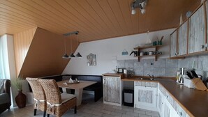 Een keuken met een houten aanrecht, een eethoek met een tafel en stoelen, en een ingebouwde bank.