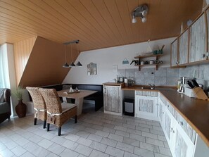 Eine Küche mit Holzausziehtisch, ein Essbereich mit Tisch und Stühlen sowie eine integrierte Sitzbank.
