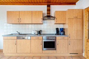 Cozinha moderna com armários de madeira, forno de aço inoxidável e cafeteira.