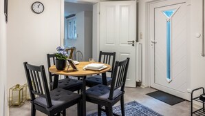 A dining area with a round table, four chairs, a clock, and a door with a blue accent. - Apartment 'Gemütliche Unterkunft' with Private Terrace, Private Garden and Wi-Fi (Quickborn)