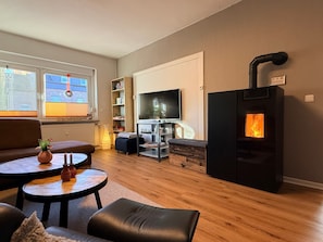 A living room with a sofa, a coffee table, a TV, a fireplace, and a bookshelf. - Apartment 'Glückauf' with Wi-Fi (Castrop-Rauxel)