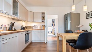 A modern kitchen with white cabinets, a wooden countertop, and a dining area with a table and chairs. - Apartment 'Glückauf' with Wi-Fi (Castrop-Rauxel)